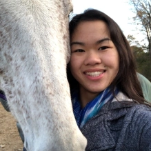 smiling woman next to a white horse