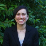 Smiling person in front of green leafy bush