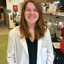 Smiling woman wearing a lab coat in a research lab