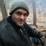 Man sitting outside with a jacket and stocking cap on